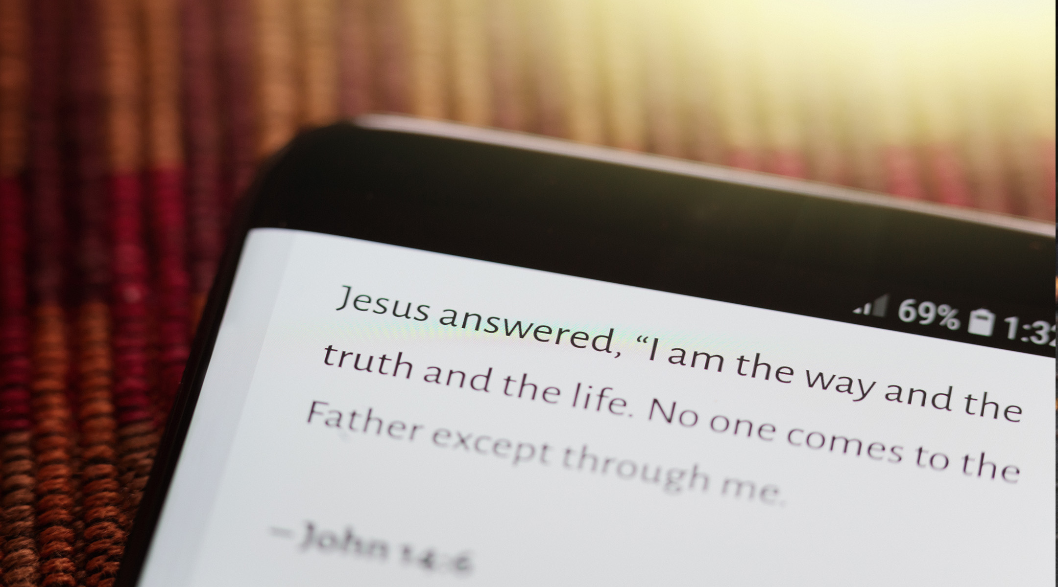 Person using a Bible study app on a tablet with open Bible nearby