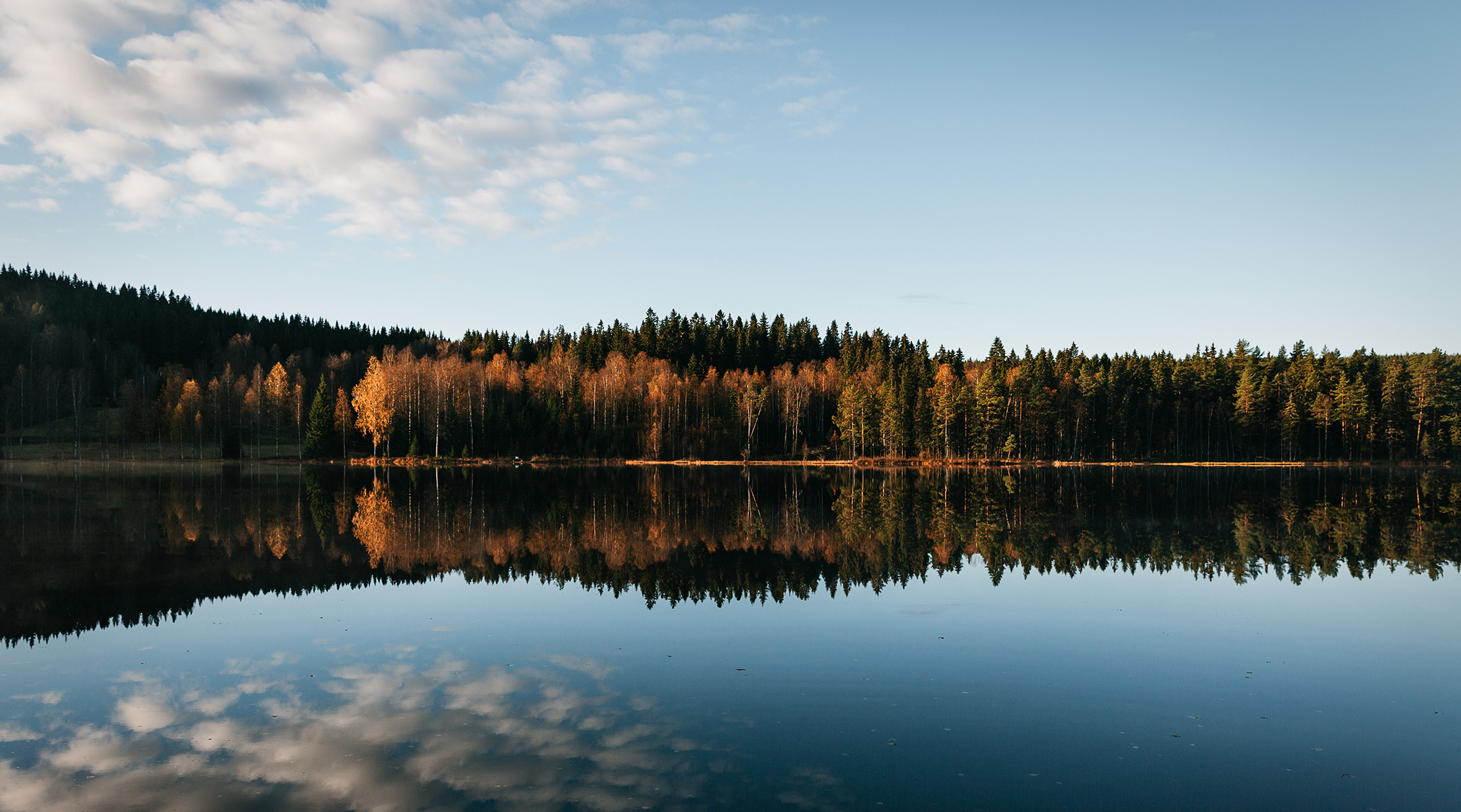 Calm lake at dawn reflecting mountains and sky
